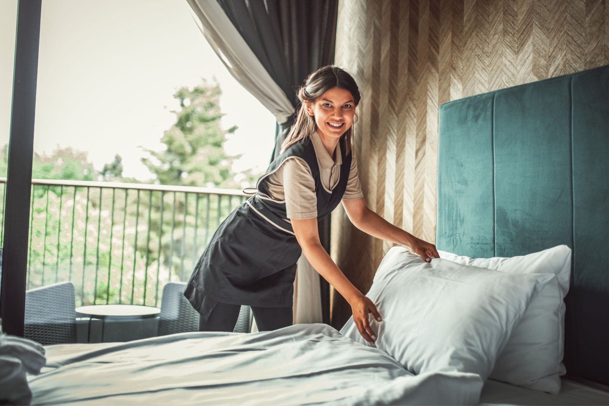 housekeeper making a bed in a guest bedroom