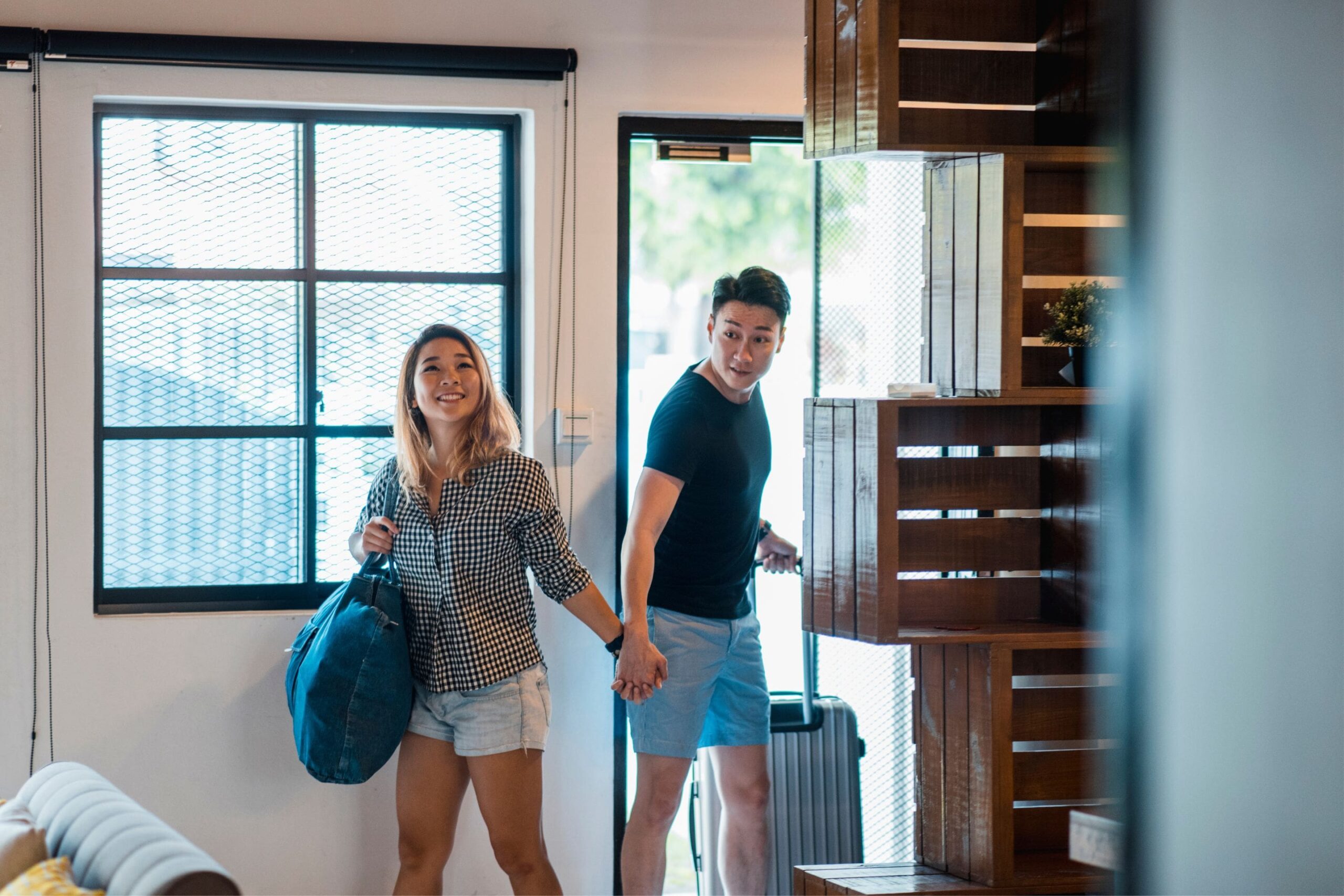 couple with a rolling suitcase in tow opening the door to their vacation rental house