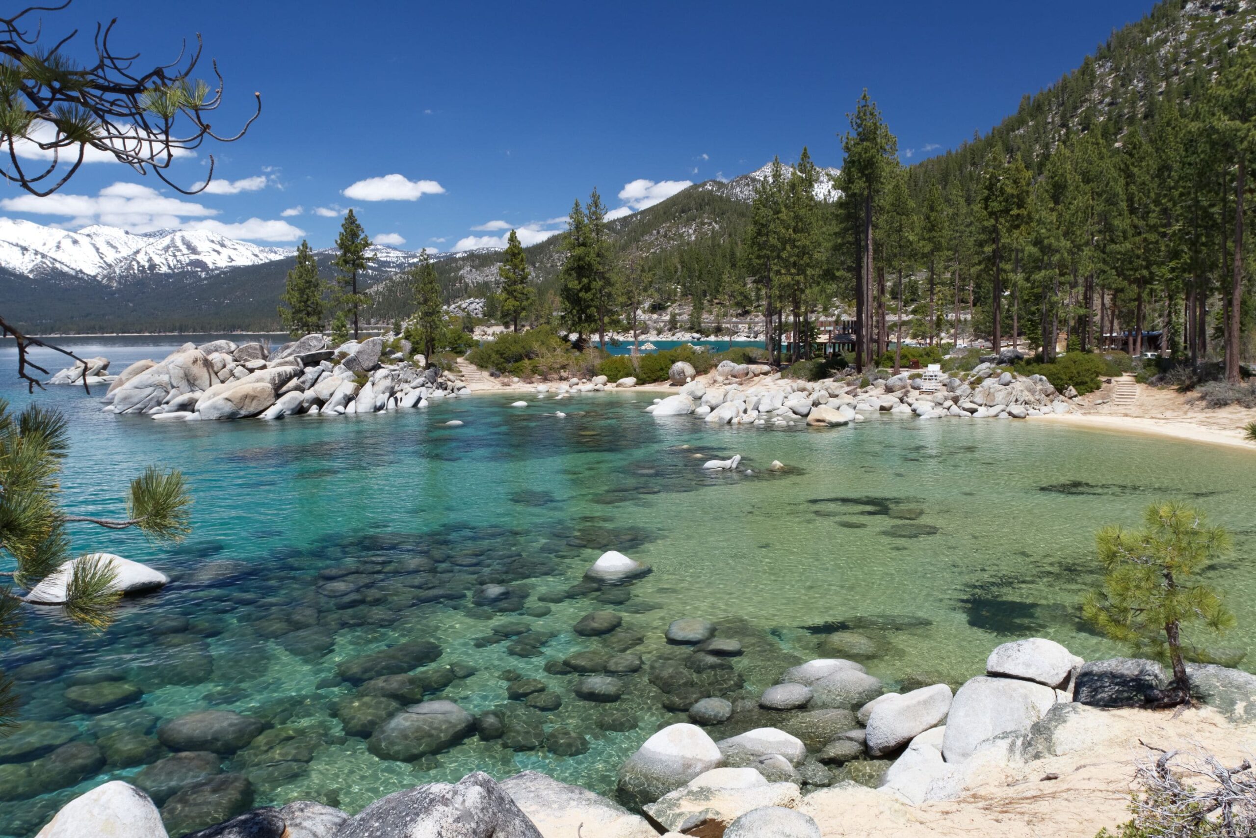 crystal clear water surrounded by a rocky shoreline and evergreen trees around Lake Tahoe