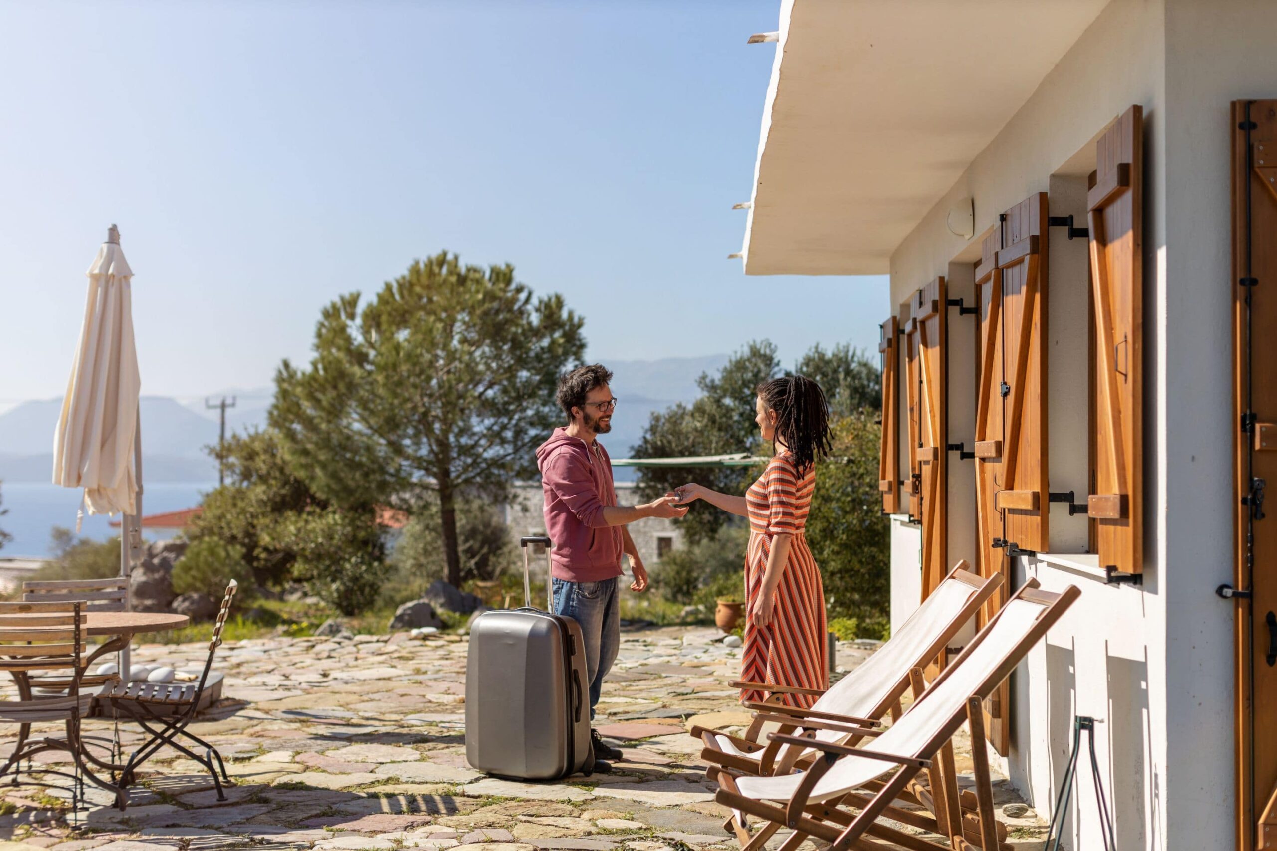 woman handing a man with a suitcase keys to a vacation rental home