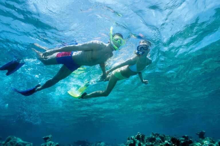 two people snorkeling above a reef shot from below