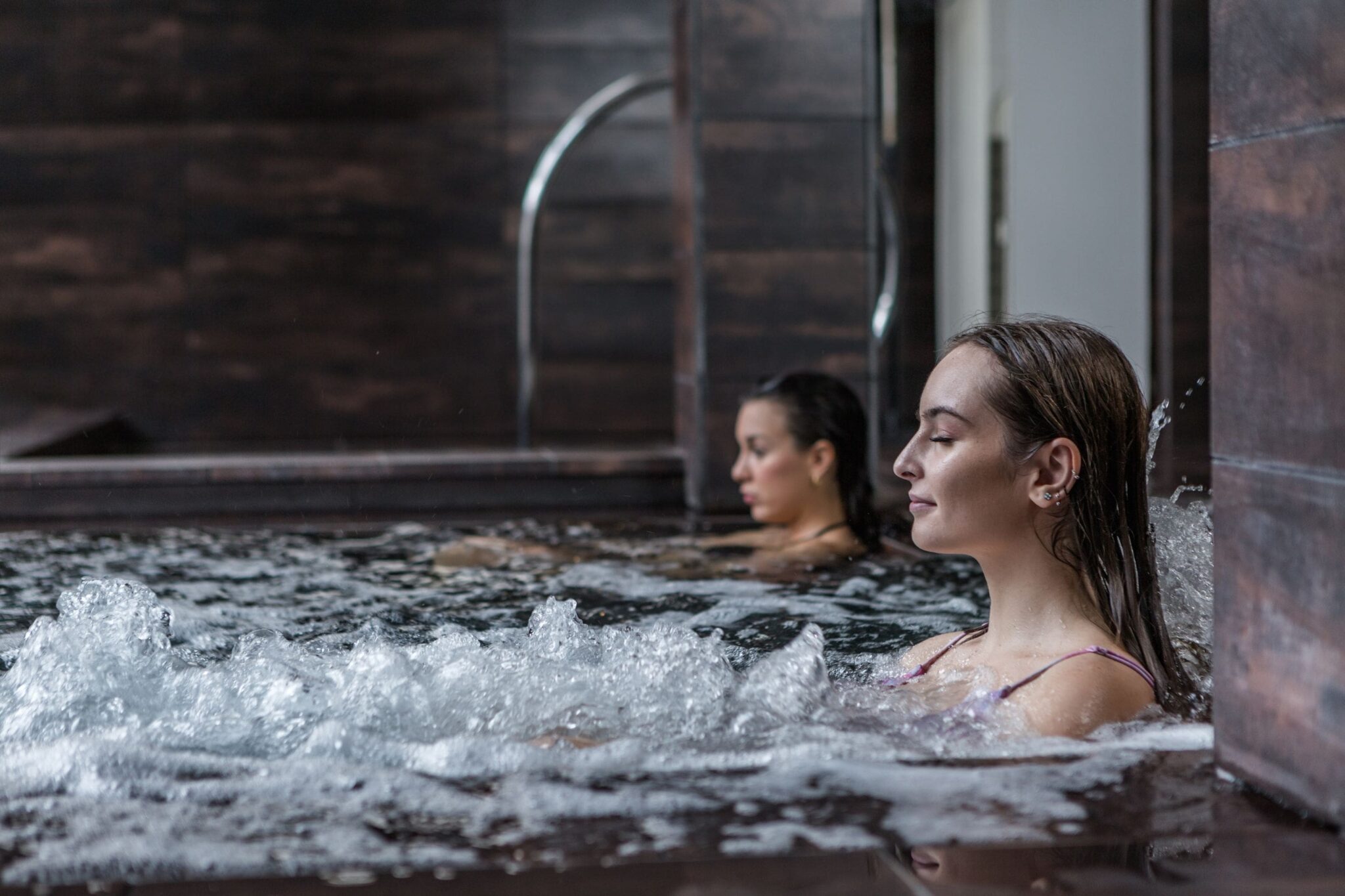 two women enjoying a relaxing soak in an indoor hot tub