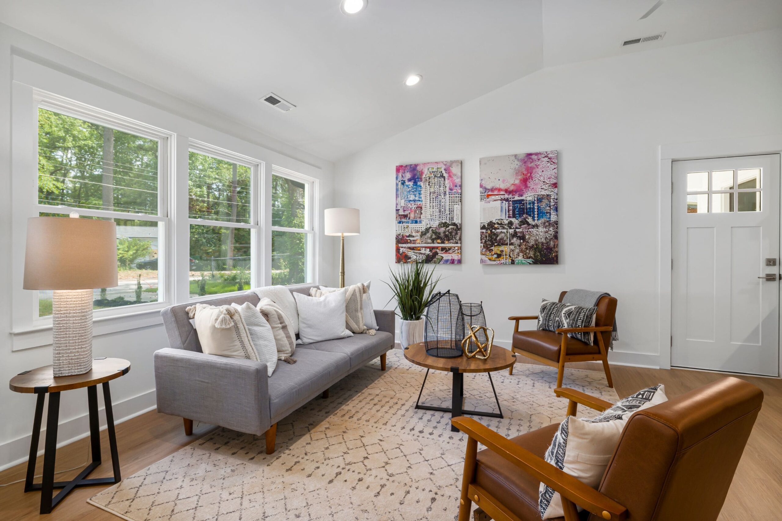 shot of a clean, minimalist design inspired living room with a couch, accent chairs and wall art