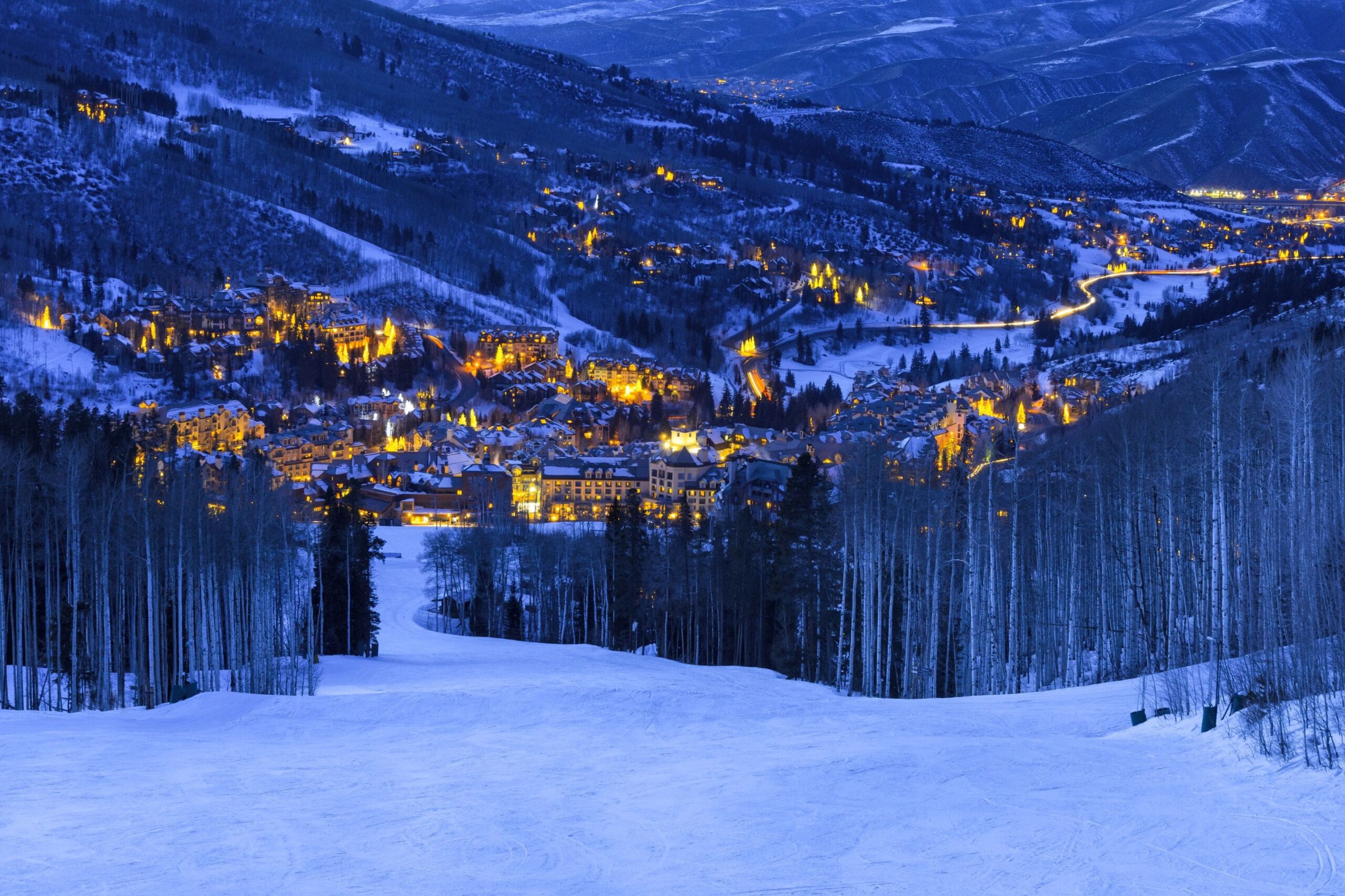 view down a ski run at dusk with the lights of Beaver Creek below