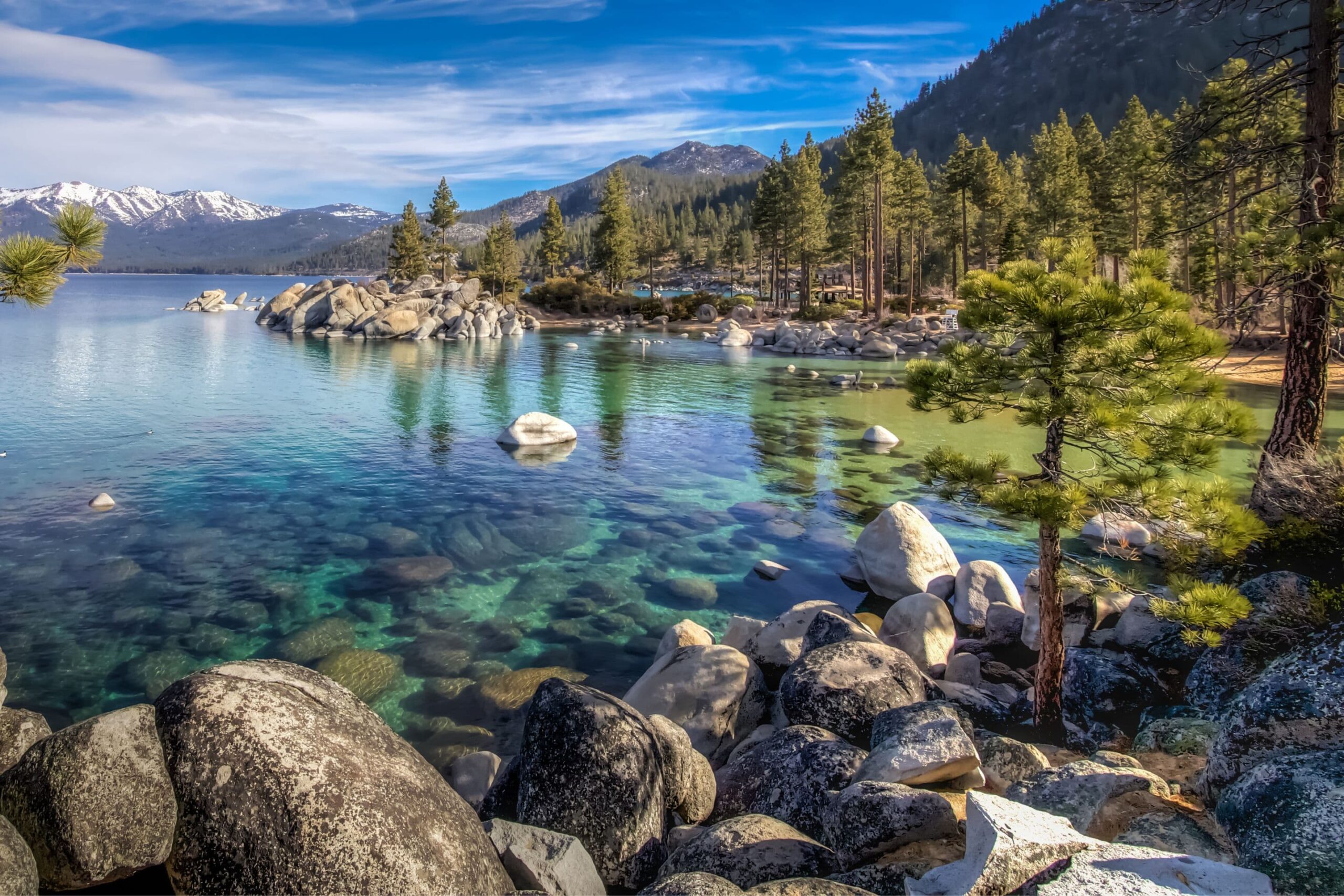 Lake Tahoe shot from the rocky shoreline with mountains in the distance