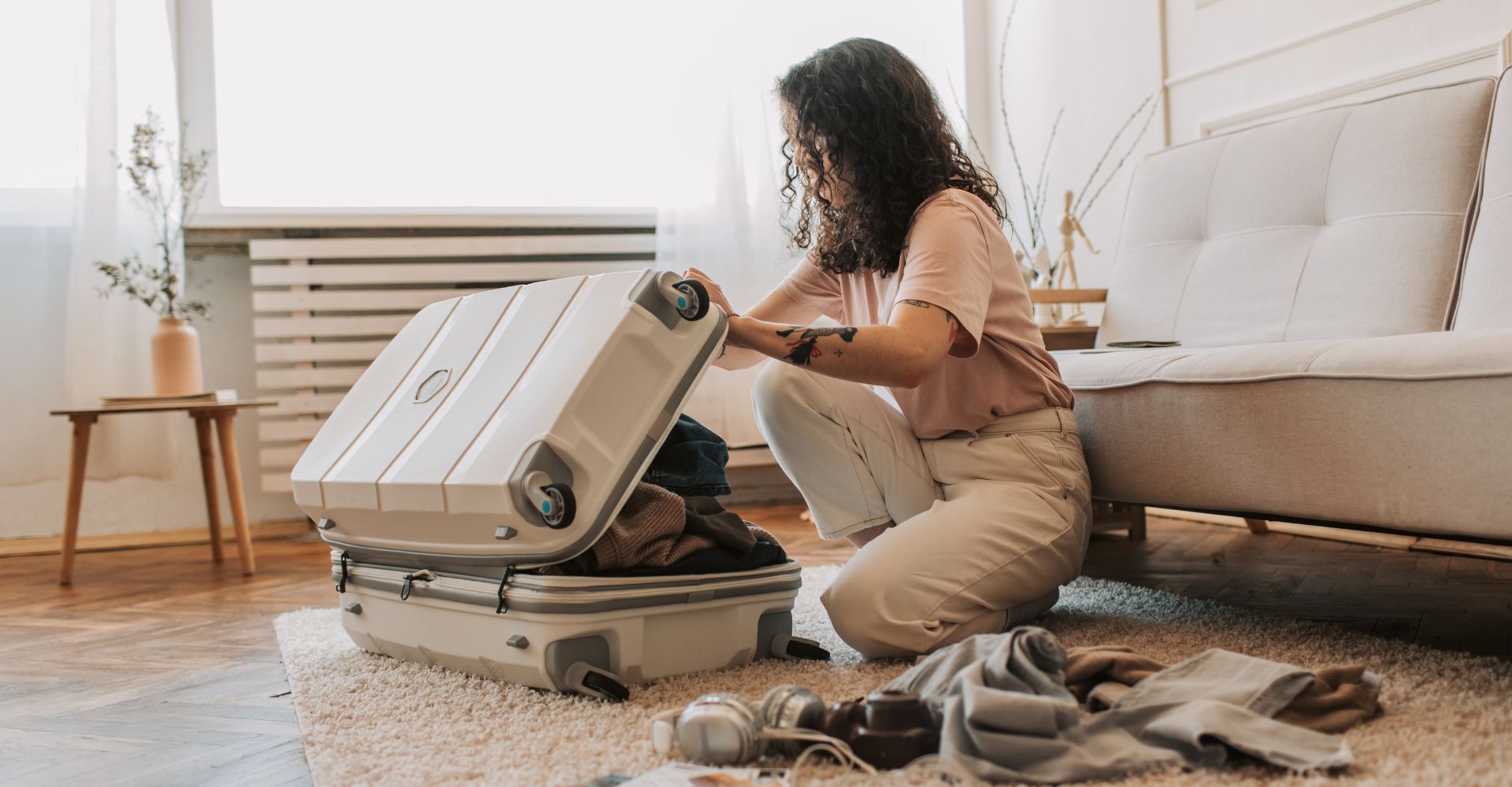 woman sitting on the floor attempting to close a packed suitcase